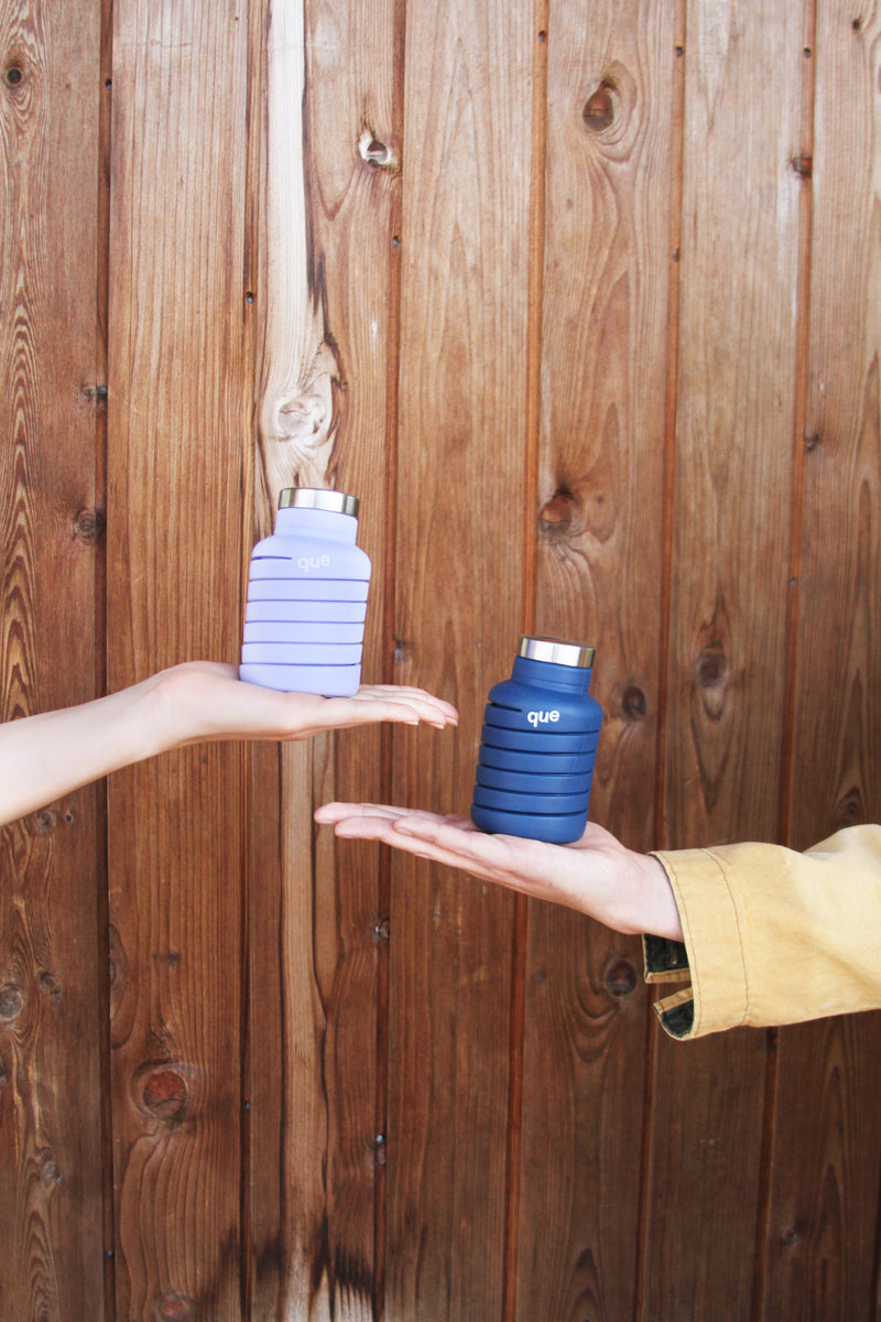 Two hands passing a collapsed que bottle