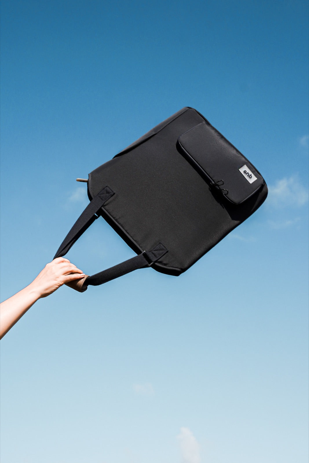 The Convertible Totepack held up against a clear blue sky